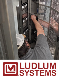 Ludlum Systems technician working on HBP-29 contamination monitor and logo